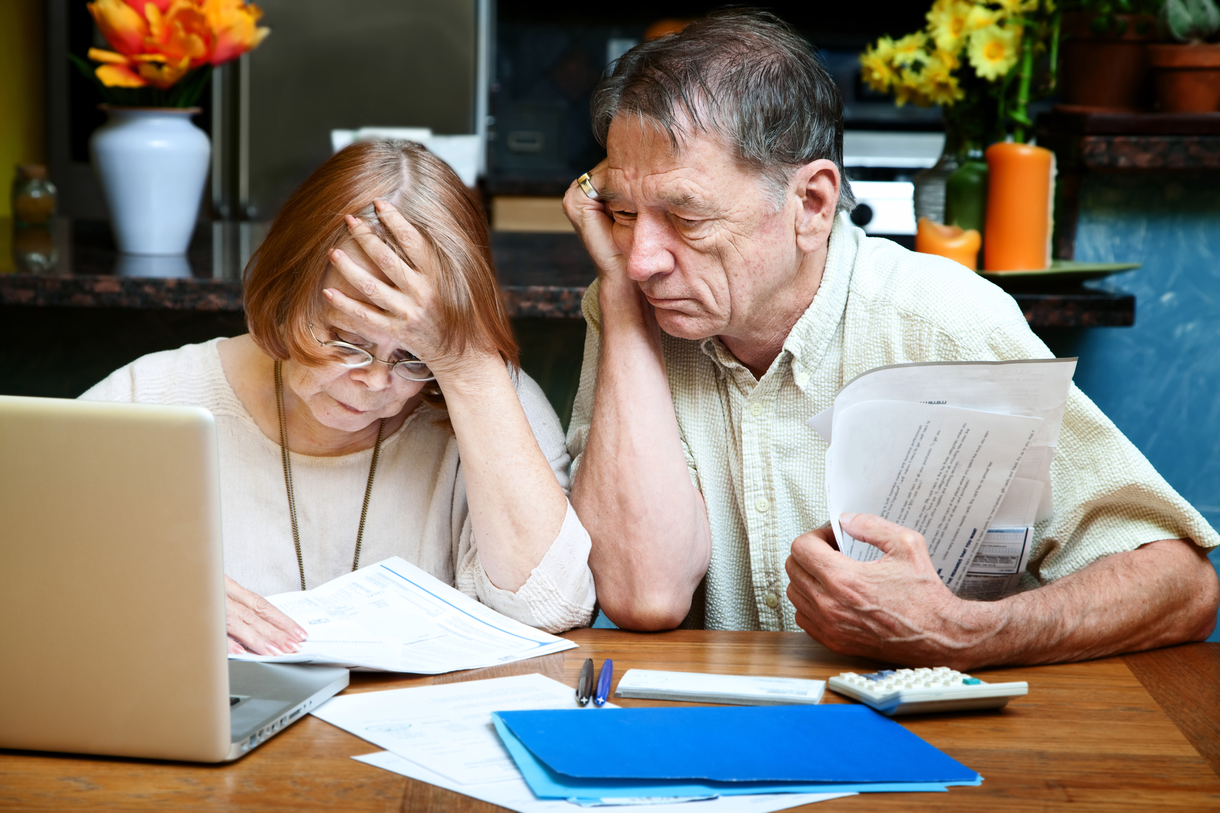 Senior couple at home reacting to many bills