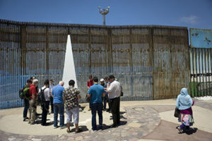 Part of a group of 16 Jesuit priests and staff from the Jesuits West province pray June 7 at the U.S.-Mexico border fence in Tijuana, Mexico. In addition to the fence, the group visited several migrant shelters and a Jesuit-run university to learn about immigration issues first hand. They are part of a larger group of Jesuits and lay people who will be in San Diego for a June 9 ordination ceremony. (CNS photo/David Maung)