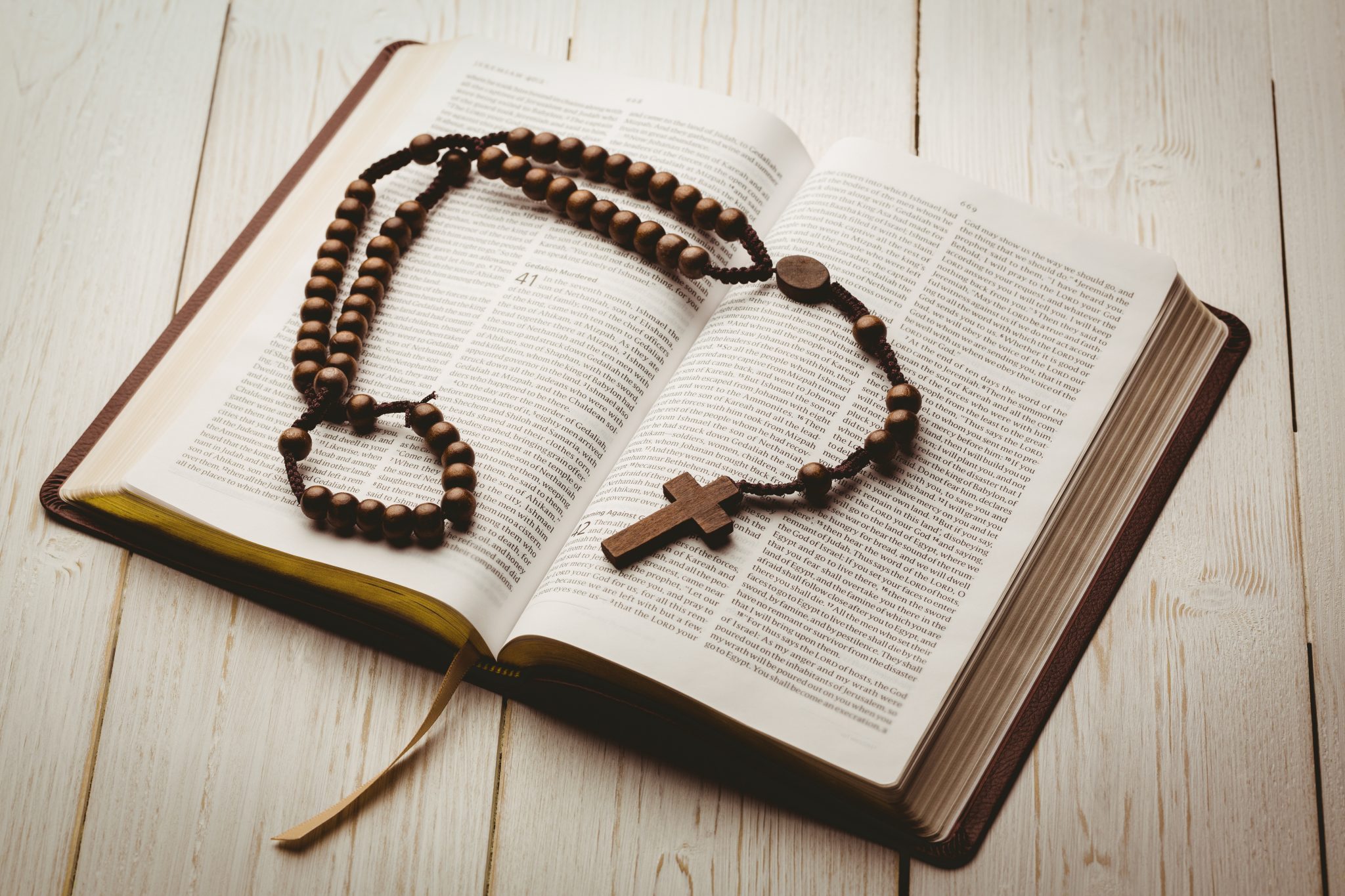 Open bible and wooden rosary beads - Texas Catholic Conference